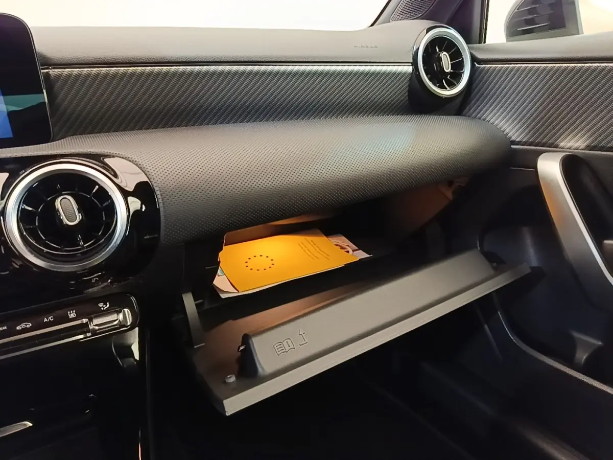 Intérieur de la Mercedes Classe A 250 e Business Line 2023, vue côté passager sur la boîte à gants ouverte et tableau de bord noir texturé.
