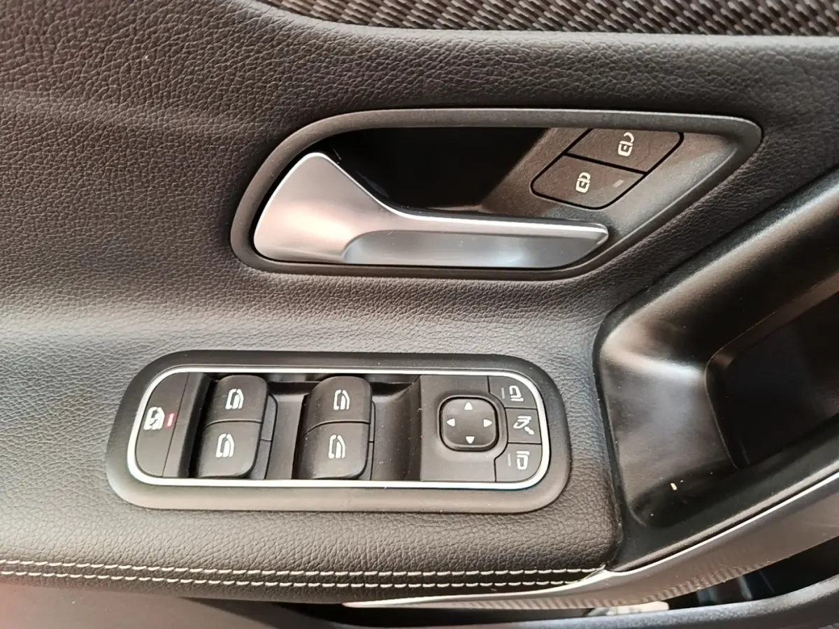 Gros plan sur la commande des vitres et poignée intérieure en cuir noir sur la porte côté gauche de la Mercedes Classe A 250 e.