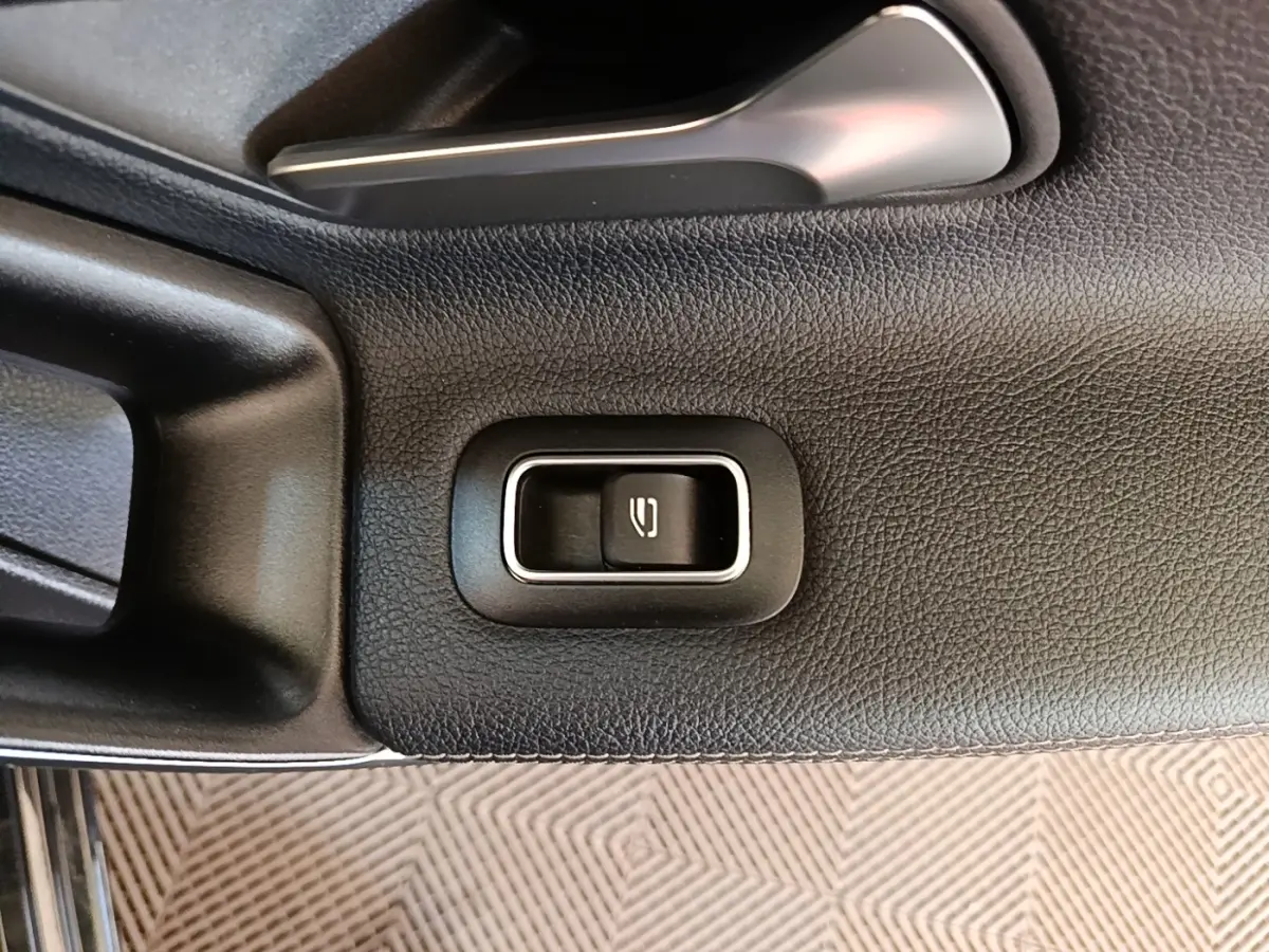 Détail de la commande d'ouverture du coffre sur la porte intérieure noire d'une Mercedes Classe A 250 e Business Line 2023.
