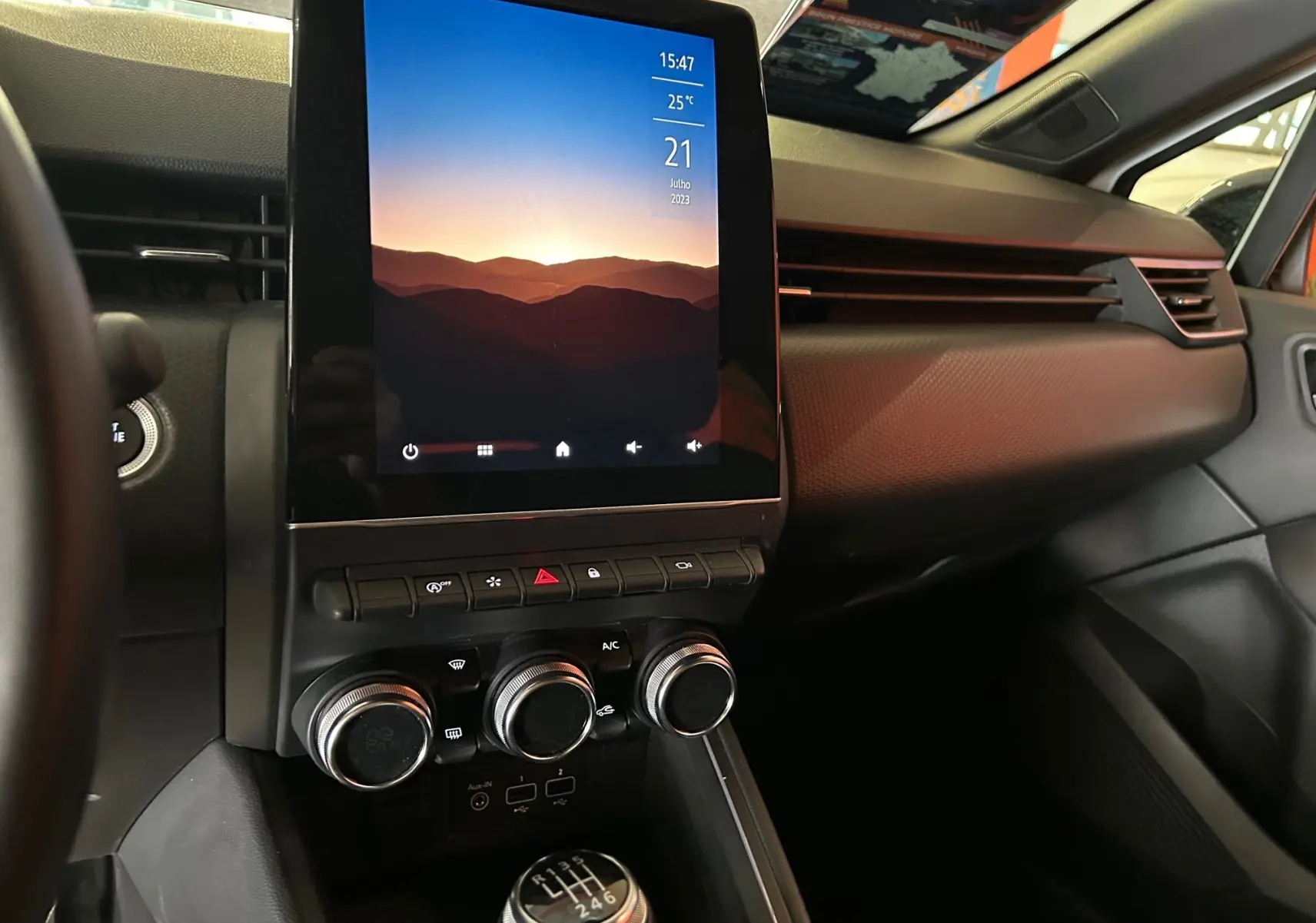 Vue rapprochée de la console centrale et levier de vitesse manuel de la Renault Clio V blanc nacré, avec écran tactile allumé.