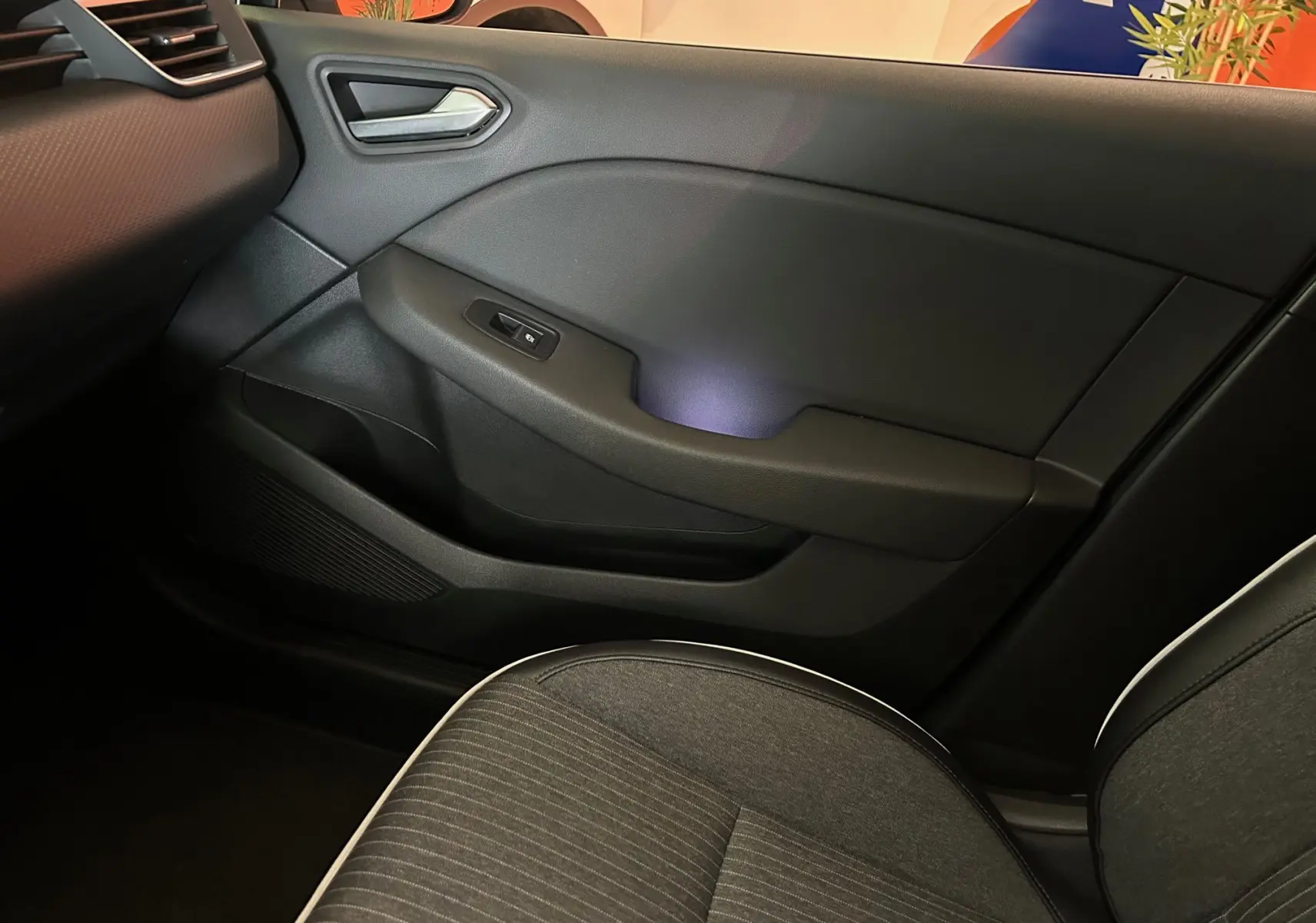 Détail de la porte intérieure côté droit de la Renault Clio V 2021 avec tissu gris et éclairage d'ambiance violet.