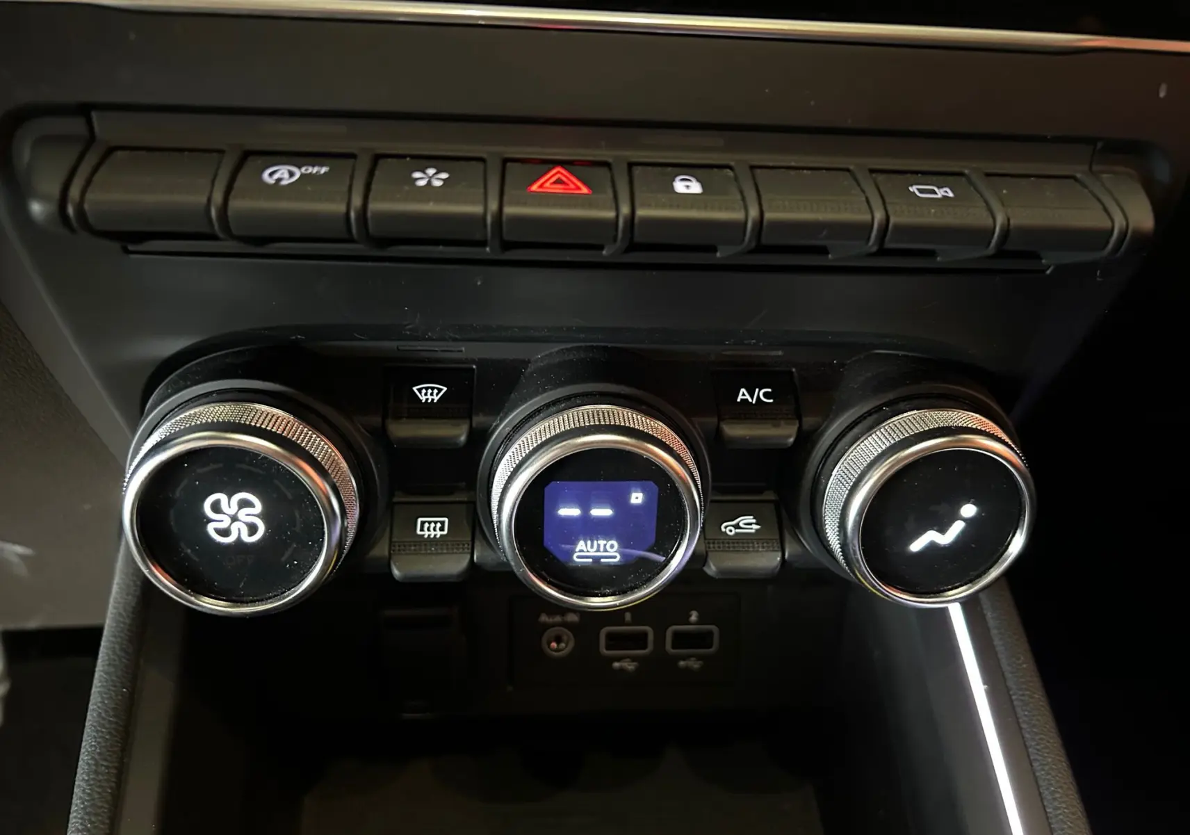 Gros plan sur la console centrale de la Renault Clio V 1.0 TCE 90 CH Intens, avec commandes de climatisation et boutons fonctionnels.