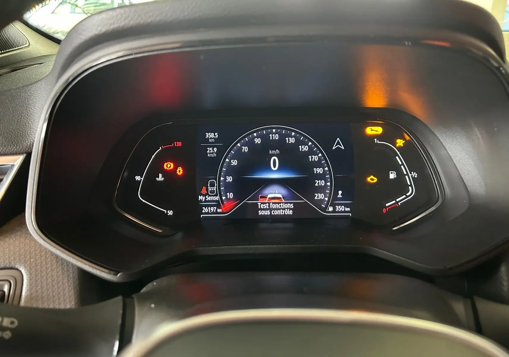 Tableau de bord numérique de Renault Clio V blanc nacré, affichant vitesse zéro et témoins d'alerte allumés.