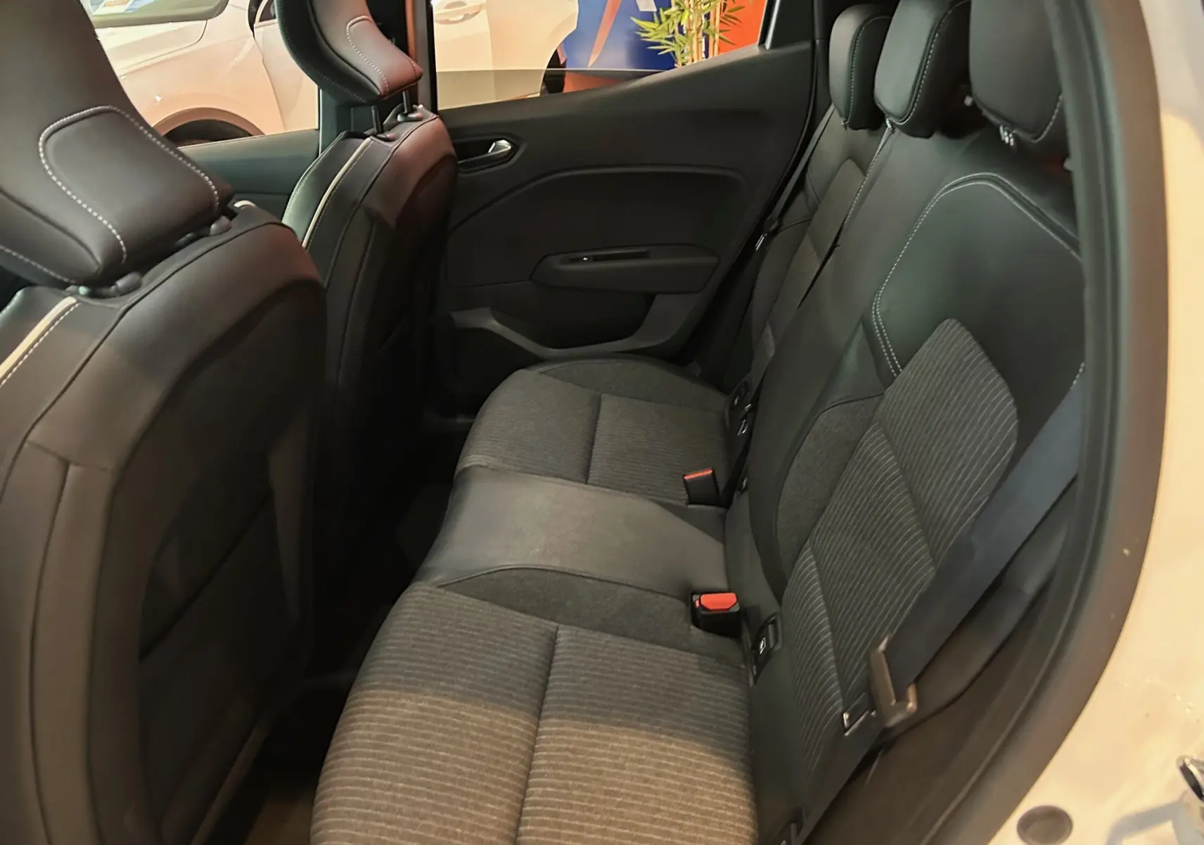 Vue intérieure côté droit sur la banquette arrière en tissu gris et cuir noir de la Renault Clio V blanc nacré.