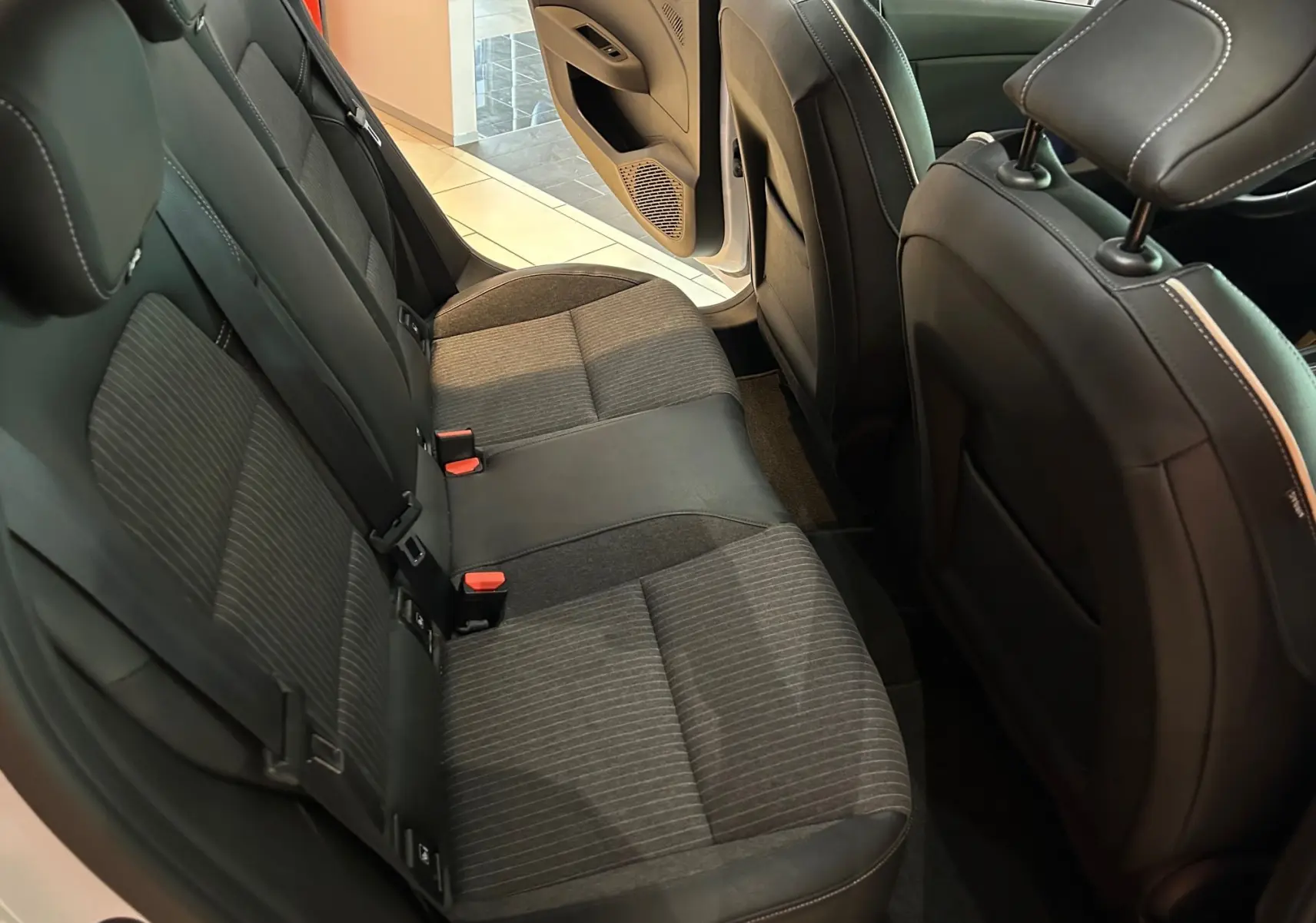 Vue intérieure arrière côté gauche de la Renault Clio V 2021, sièges tissu gris et cuir noir, porte ouverte.