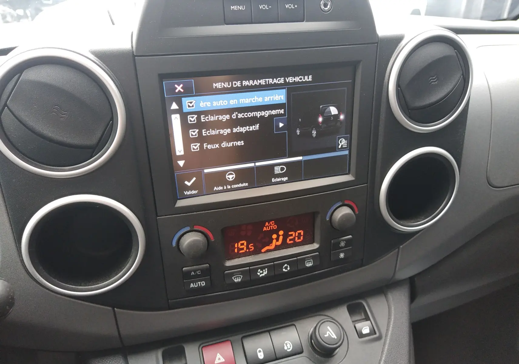 Vue rapprochée du tableau de bord du Peugeot Partner Tepee brun, avec écran tactile et commandes de climatisation visibles.
