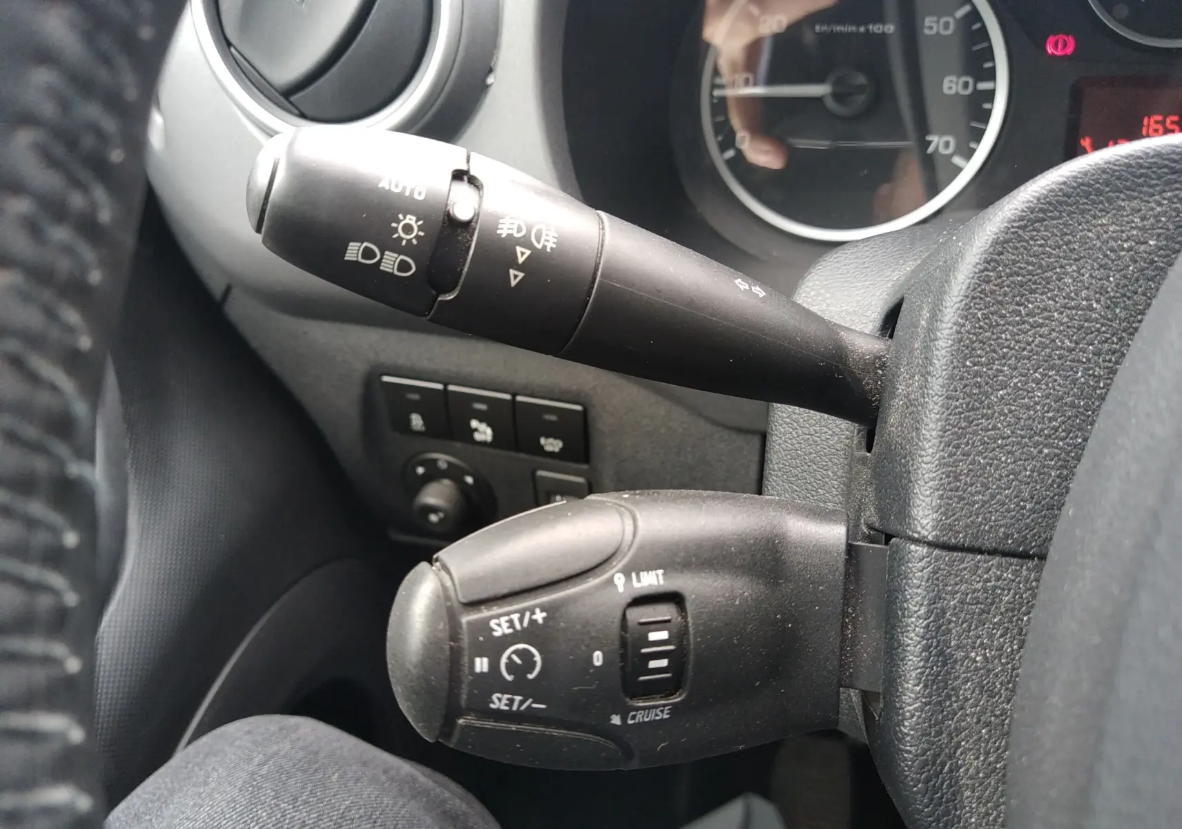 Gros plan sur les commandes de régulateur de vitesse et feux du Peugeot Partner Tepee brun, côté gauche du volant.