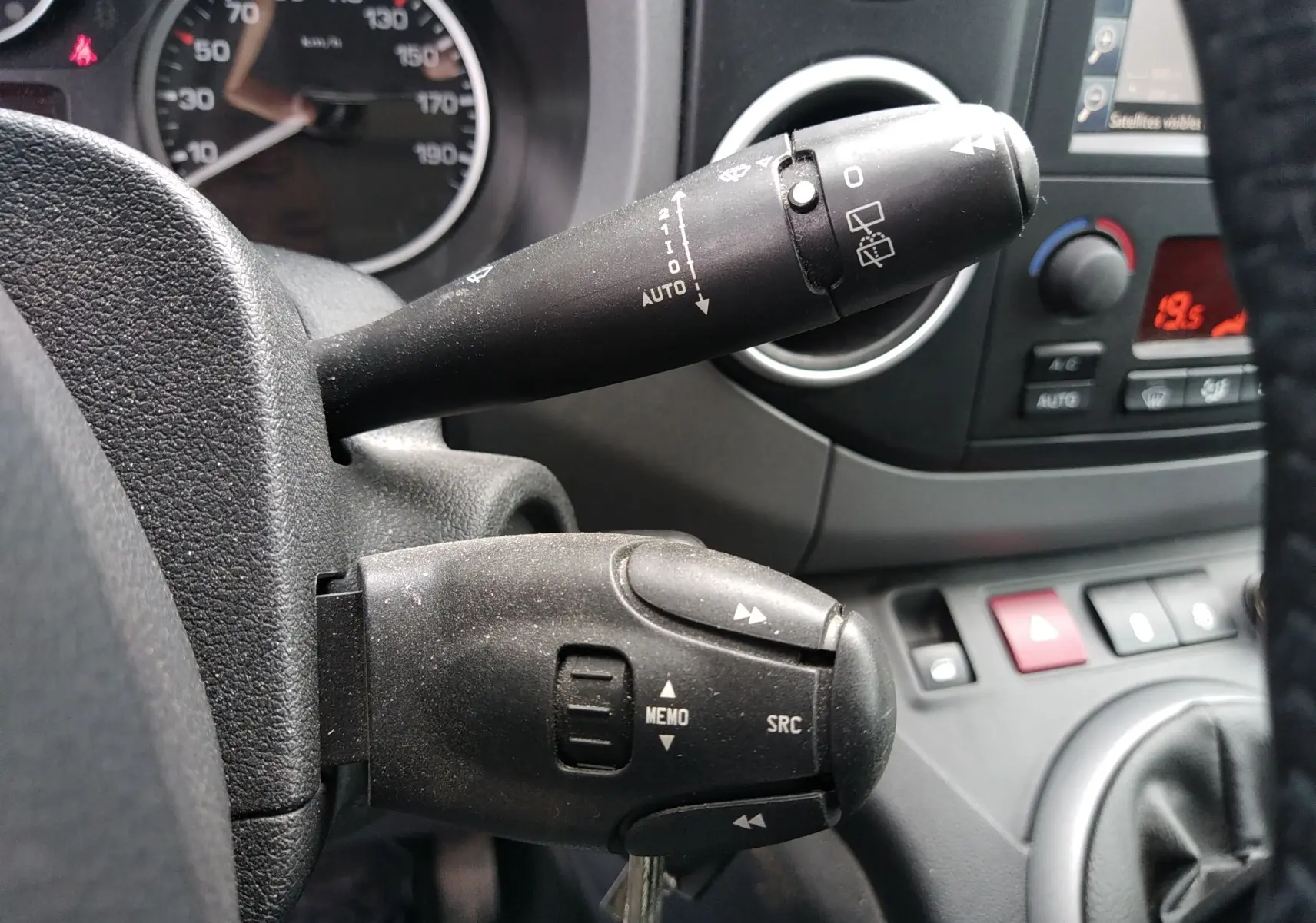 Gros plan sur les commandes au volant du Peugeot Partner Tepee brun 2017, avec tableau de bord et console visibles en arrière-plan.