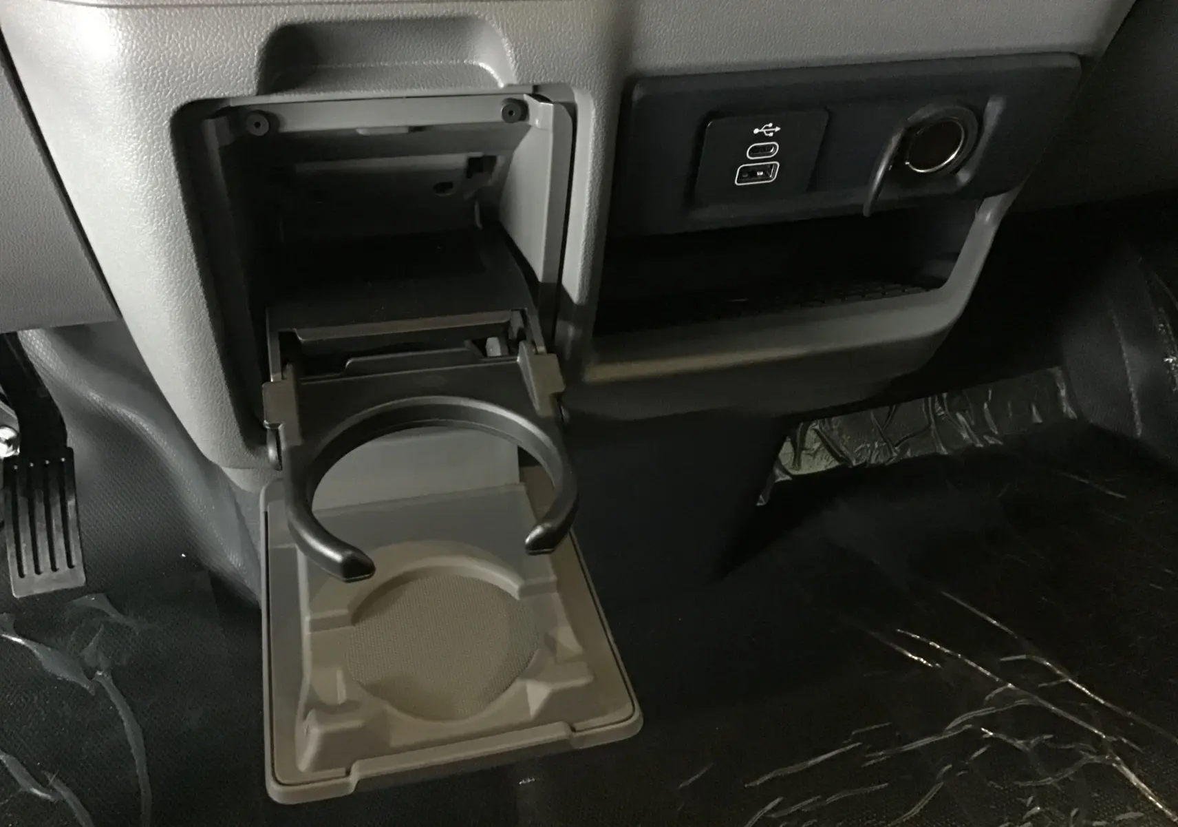 Porte-gobelet déployé côté passager du Volkswagen Transporter T7 gris anthracite, avec prises USB et allume-cigare visibles.