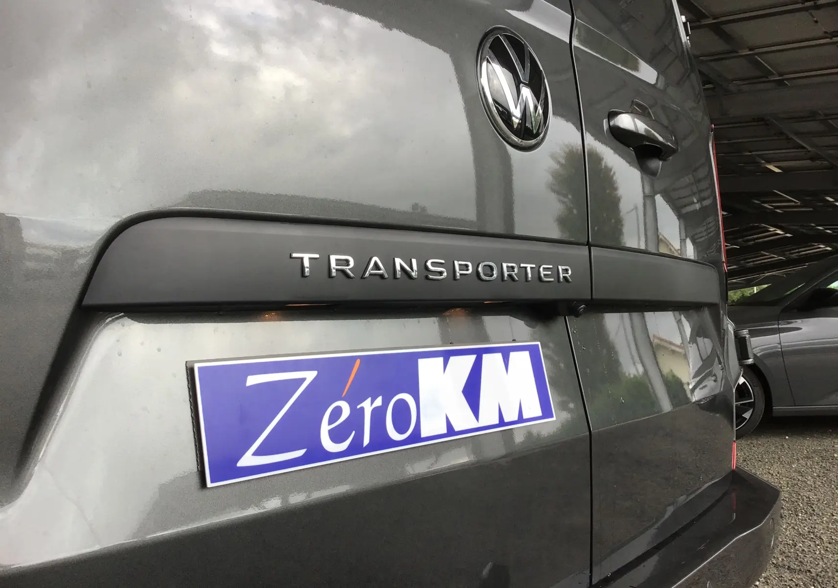 Gros plan sur l'arrière gris anthracite du Volkswagen Transporter T7 avec logo et plaque Zéro KM visible.