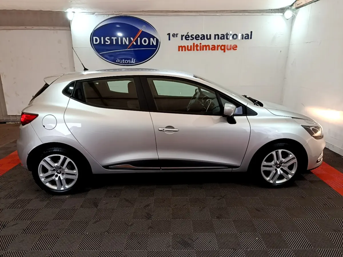 Profil côté gauche d'une Renault Clio Business TCe 90 gris clair 2019, avec jantes alliage et feux arrière allumés.