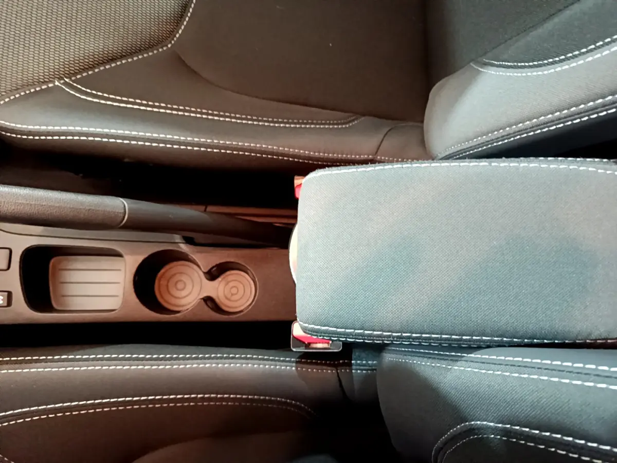 Gros plan sur l'accoudoir central et porte-gobelets entre les sièges avant gris clair de la Renault Clio Business TCe 90.