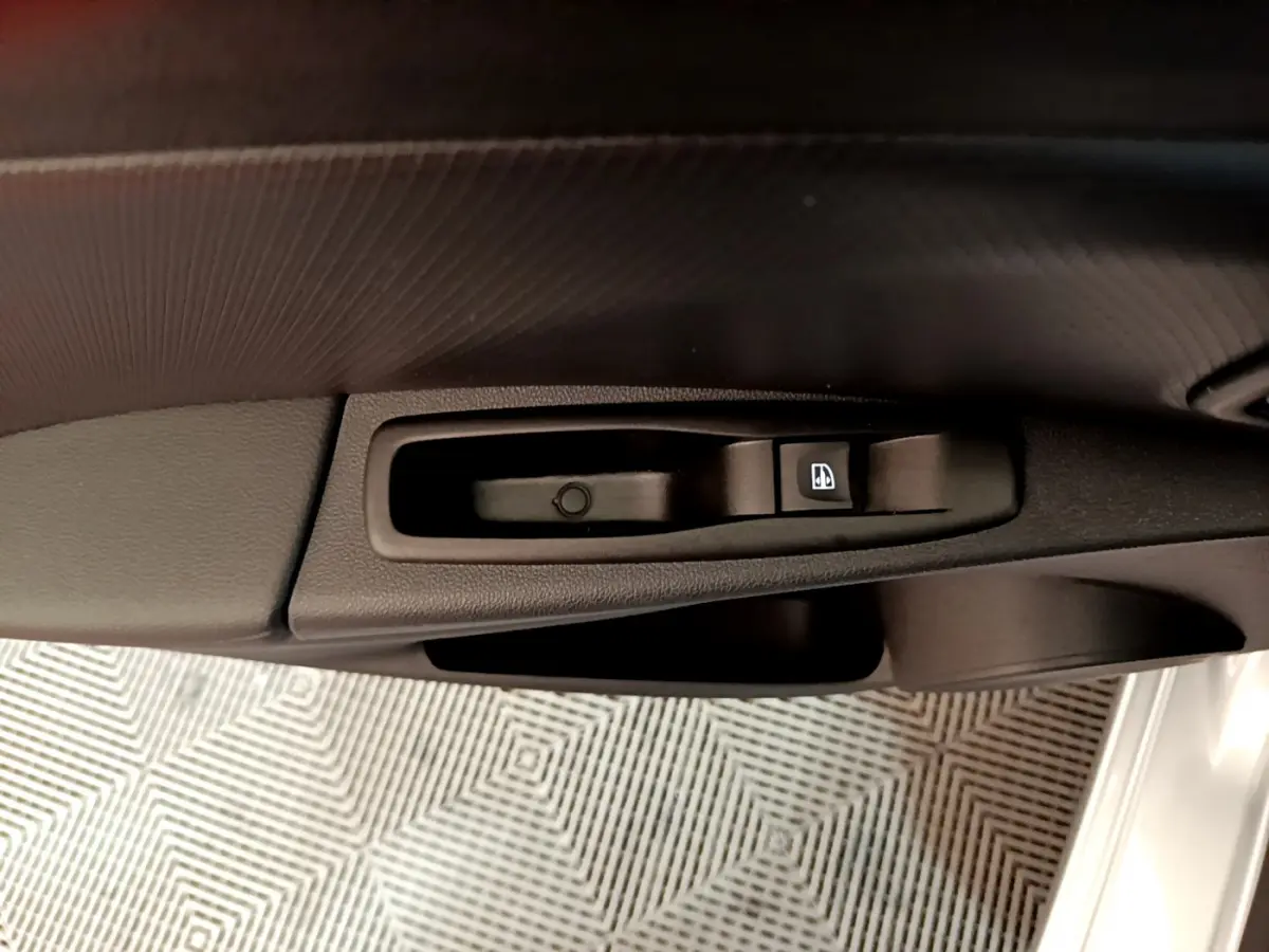 Gros plan sur la commande de lève-vitre côté conducteur d'une Renault Clio Business gris clair, intérieur noir.