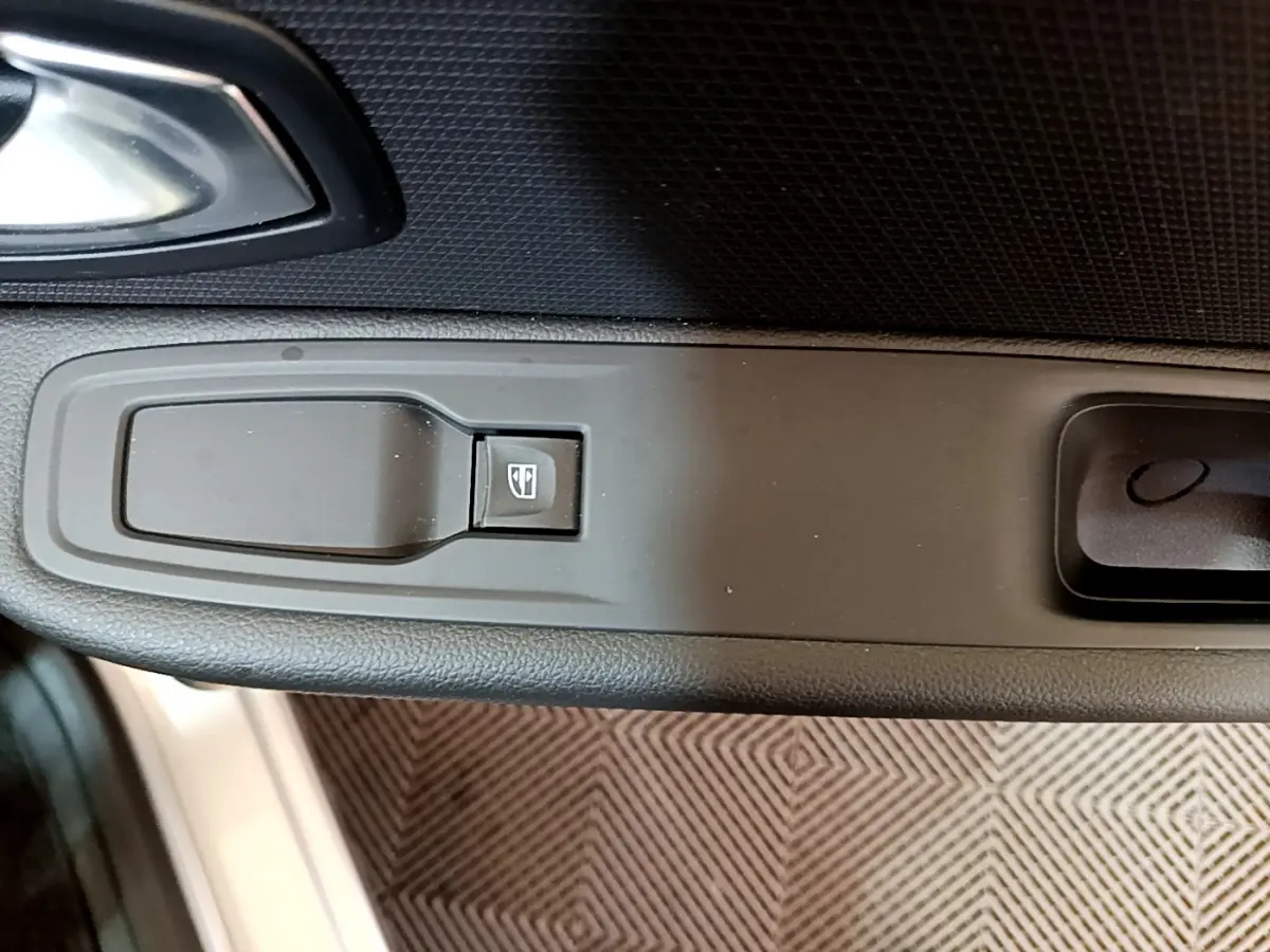 Bouton de commande de lève-vitre sur la portière côté conducteur d'une Renault Clio Business gris clair de 2019.