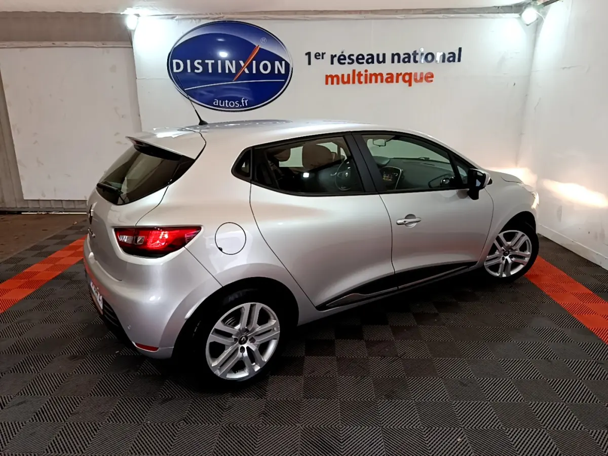 Renault Clio Business TCe 90 gris clair vue 3/4 arrière droit en intérieur avec feux arrière allumés