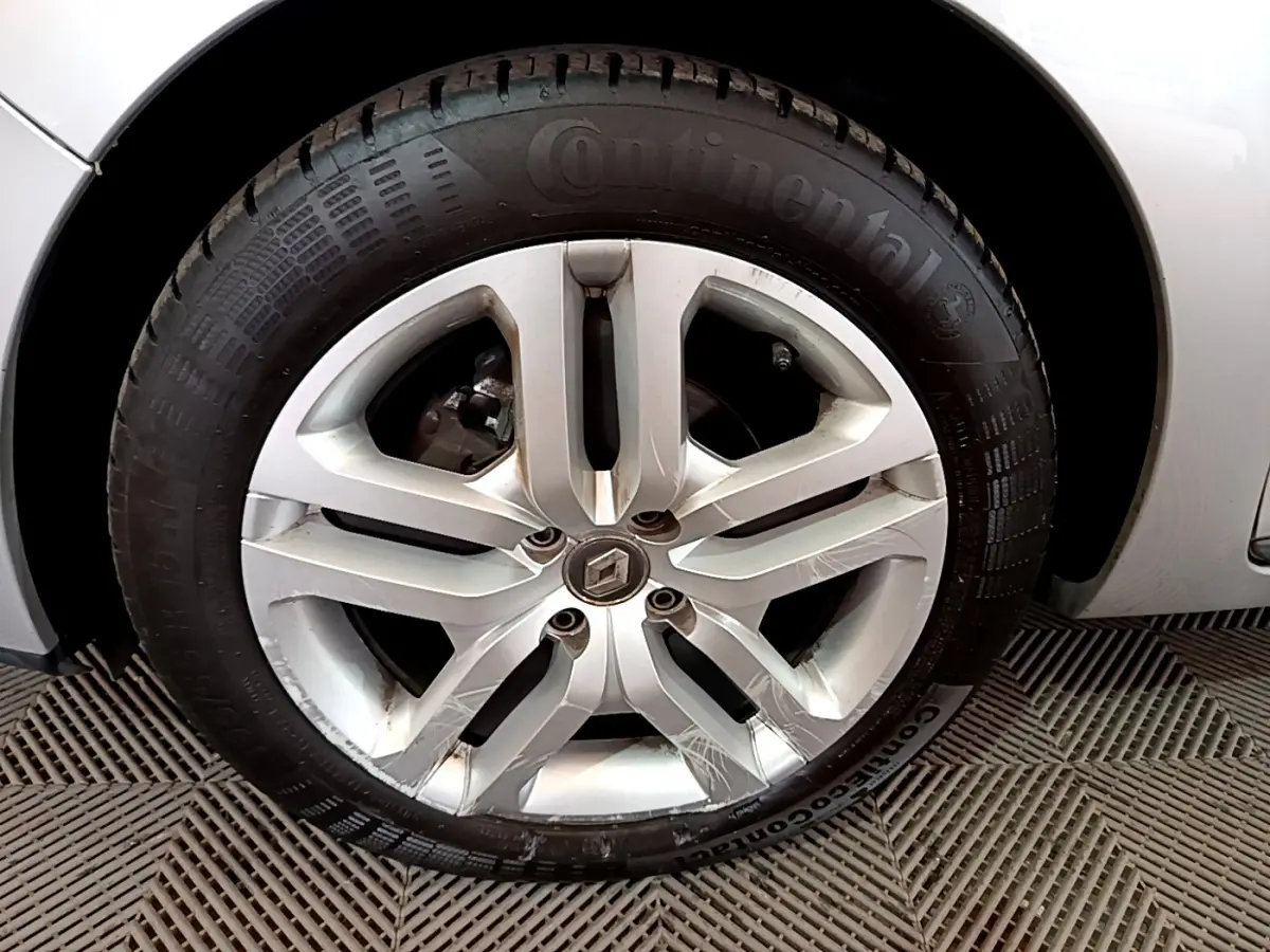 Gros plan sur la roue avant gauche d'une Renault Clio Business TCe 90 gris clair, avec partie de la carrosserie visible.