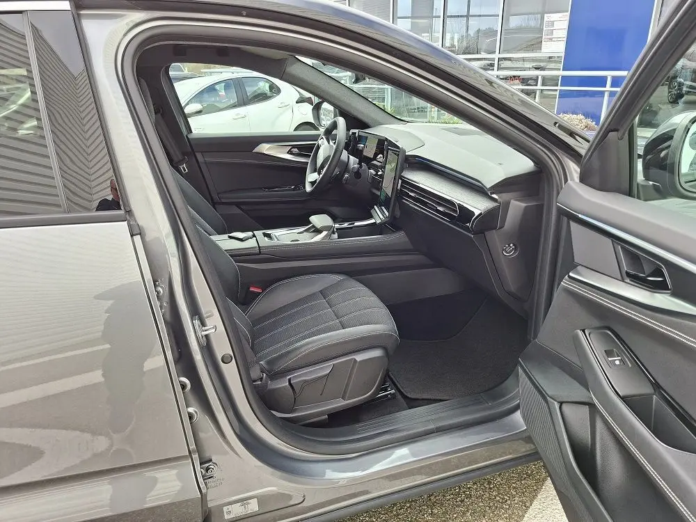 Intérieur avant droit ouvert d’un Renault Austral gris schiste, montrant les sièges noirs et le tableau de bord moderne.