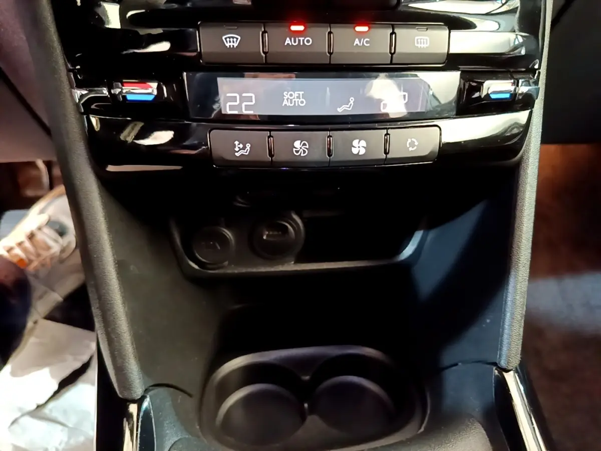 Gros plan sur la console centrale noire du Peugeot 2008 2019, montrant les commandes de climatisation digitale et les porte-gobelets.