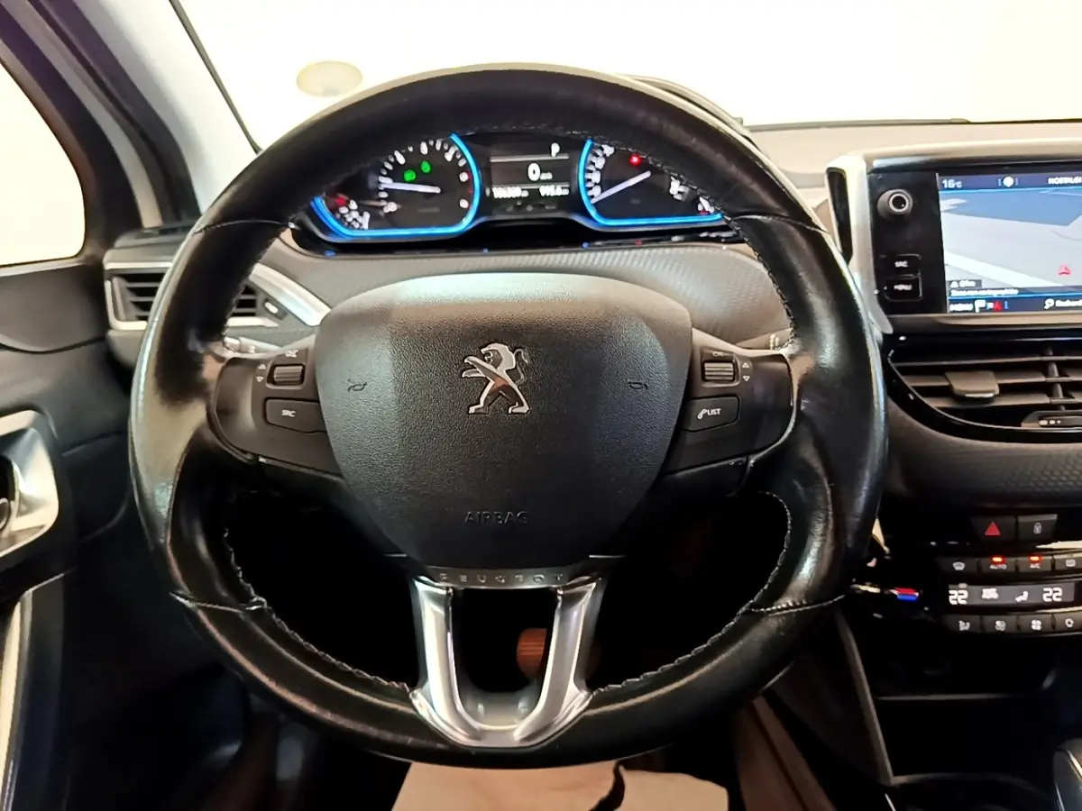 Vue rapprochée du volant cuir Peugeot 2008 2019 avec tableau de bord digital et écran tactile de navigation visible.