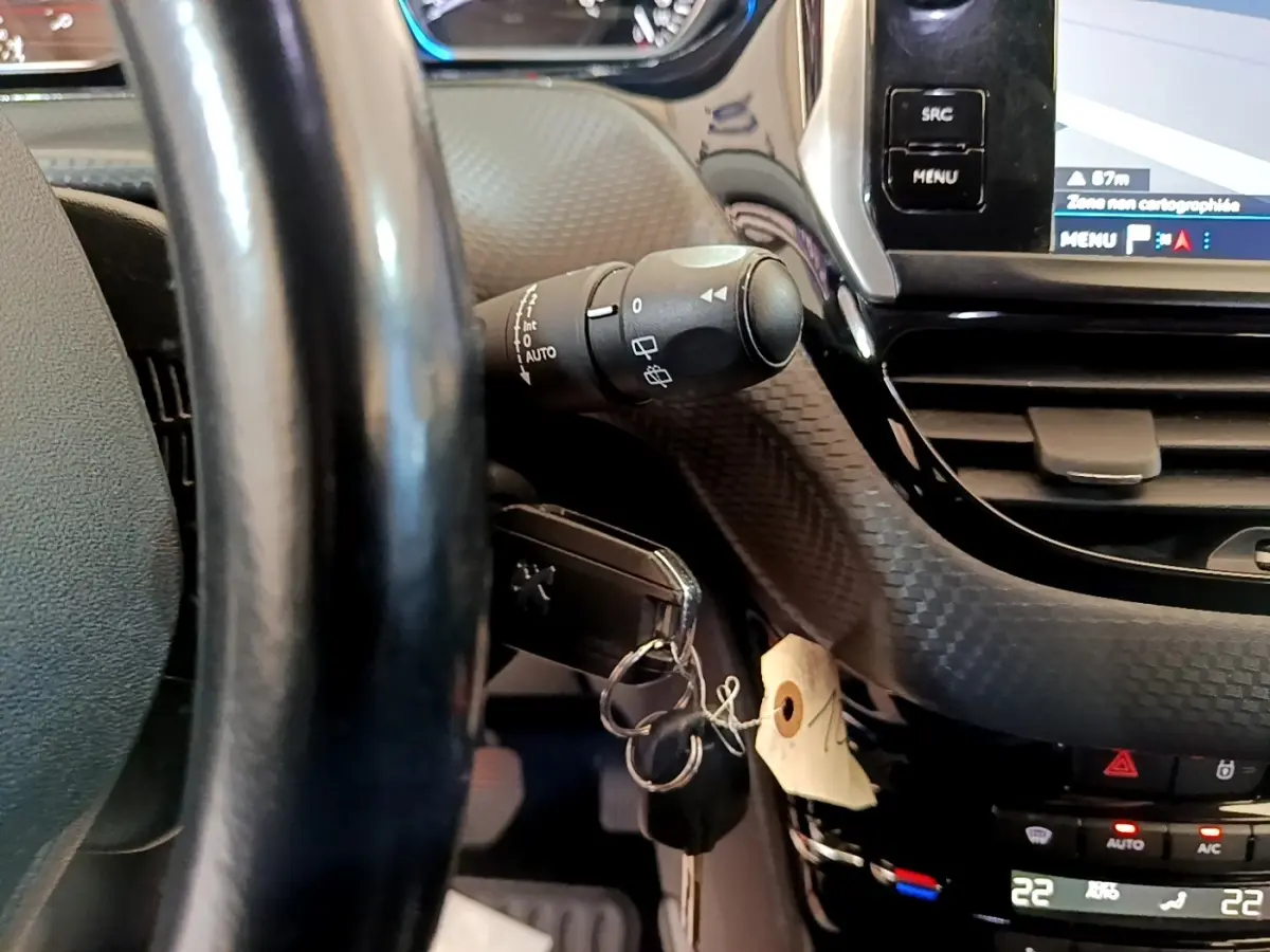 Détail intérieur du volant cuir et tableau de bord tactile du Peugeot 2008 Diesel, avec clé insérée et commandes visibles.