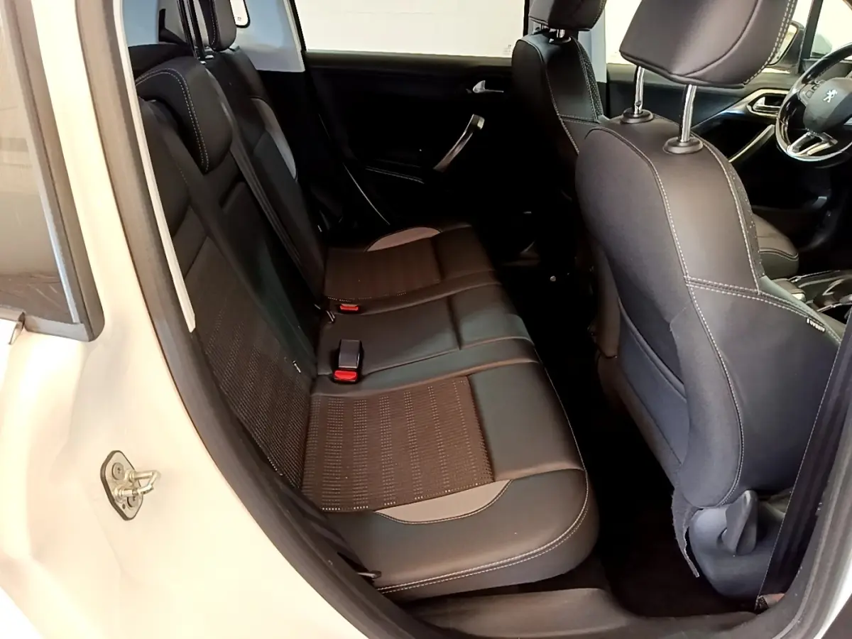 Vue intérieure côté gauche montrant la banquette arrière noire et les sièges avant d'une Peugeot 2008 blanche.