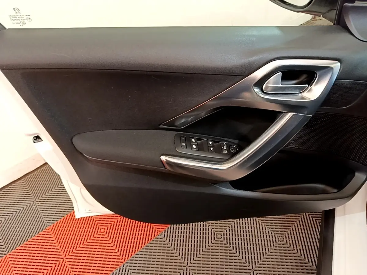 Vue intérieure de la porte avant gauche noire d'un Peugeot 2008 2019, avec commandes de vitres et poignée argentée.