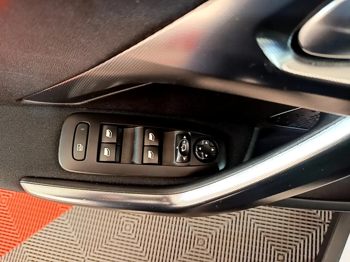 Vue rapprochée de la commande des vitres électriques côté conducteur d’un Peugeot 2008, avec poignée argentée et garniture noire.