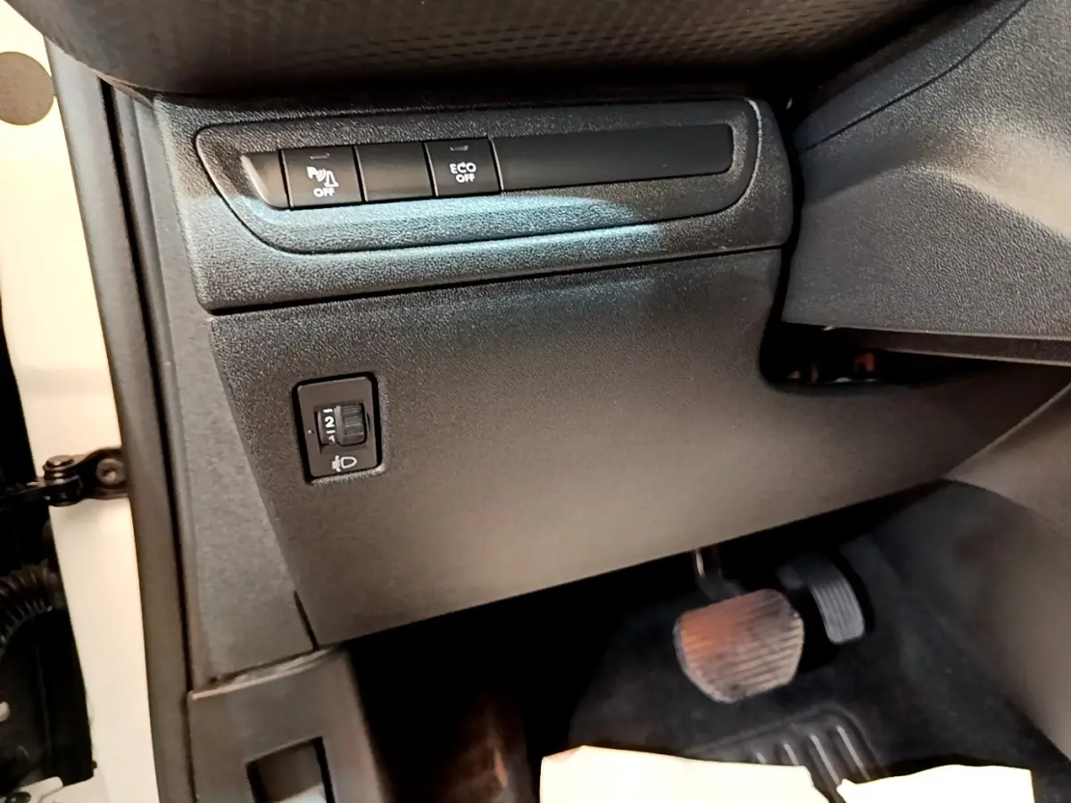 Vue intérieure côté conducteur du Peugeot 2008 2019, montrant les commandes noires sous le tableau de bord et les pédales.