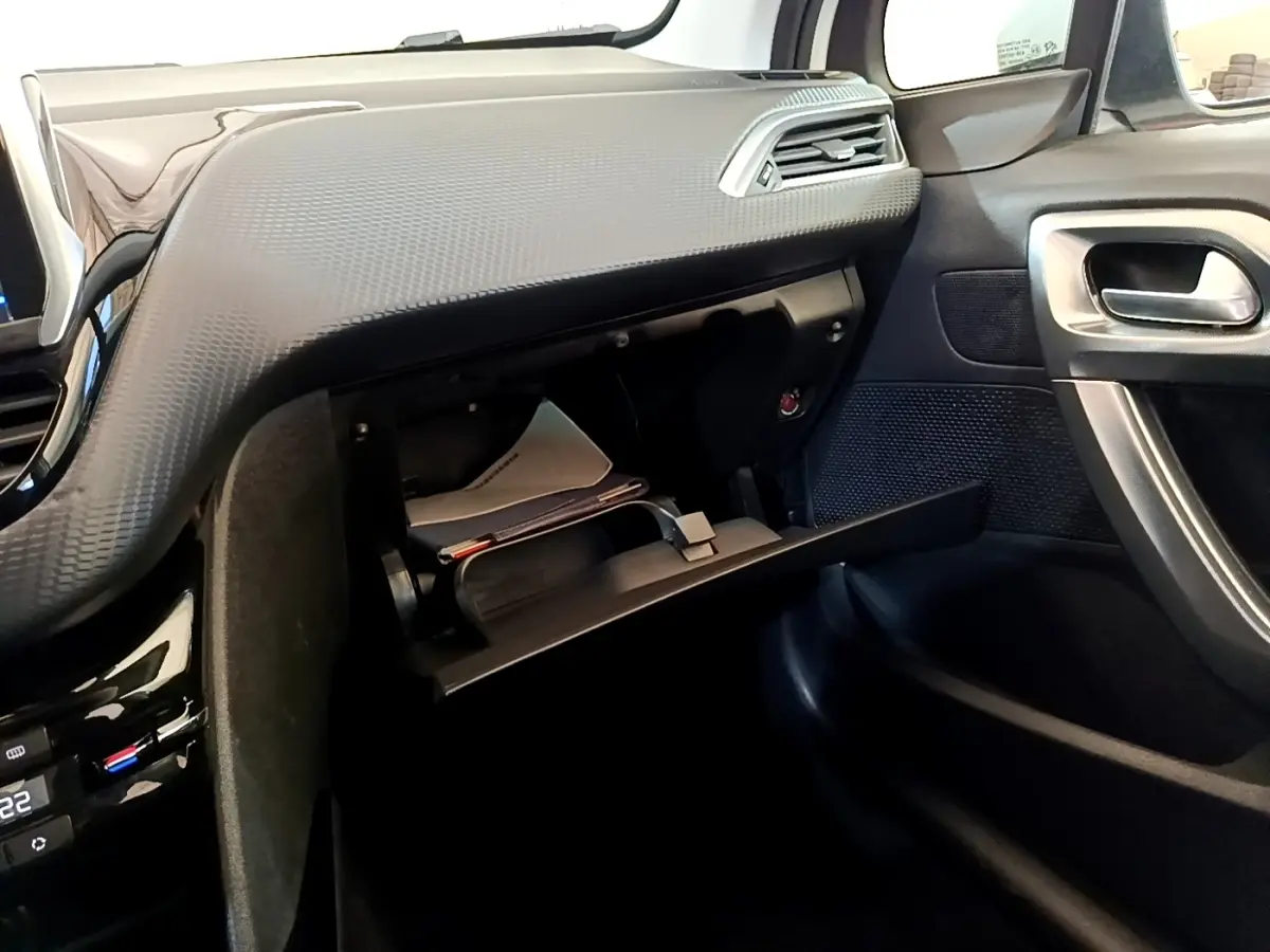 Vue intérieure côté passager du tableau de bord noir et boîte à gants ouverte du Peugeot 2008 2019 finition Allure Business.