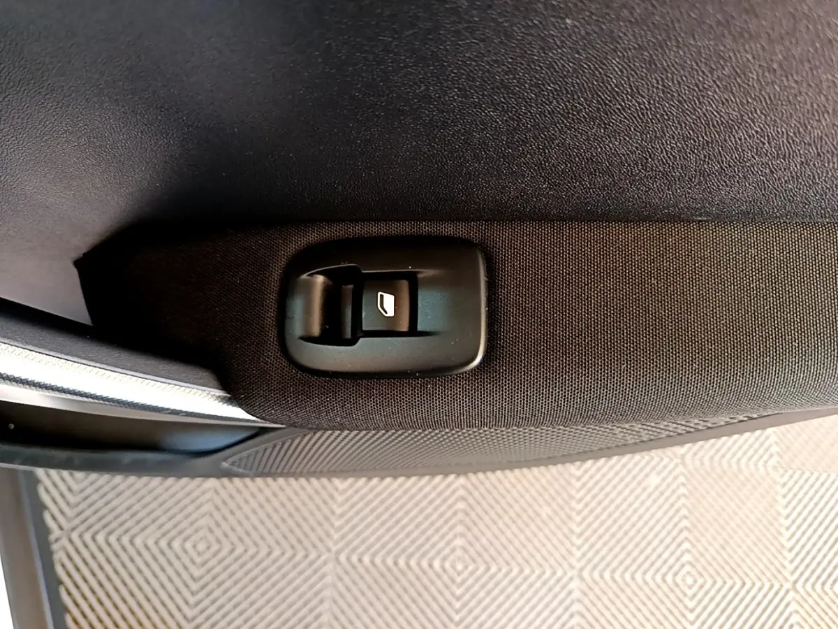 Gros plan sur le bouton de lève-vitre arrière droit en tissu noir dans une Peugeot 2008 BlueHDi 2019.
