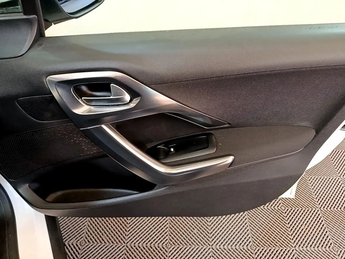 Vue rapprochée de la porte avant gauche noire du Peugeot 2008 avec poignée et commandes de vitre argentées.