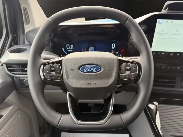 Vue rapprochée du volant multifonctions noir du Ford Transit Fourgon 2026 avec tableau de bord numérique et écran tactile central.