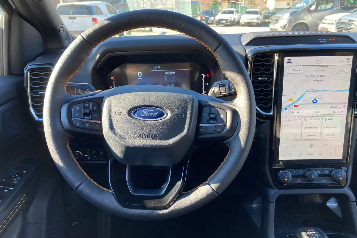 Vue intérieure centrée sur le volant du Ford Ranger 2025 noir agate avec écran tactile vertical et commandes au volant.