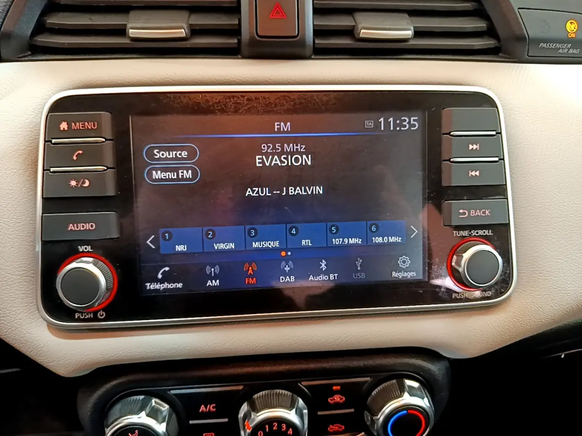 Écran tactile central de la Nissan Micra blanche 2022 affichant la radio FM et commandes audio intégrées.