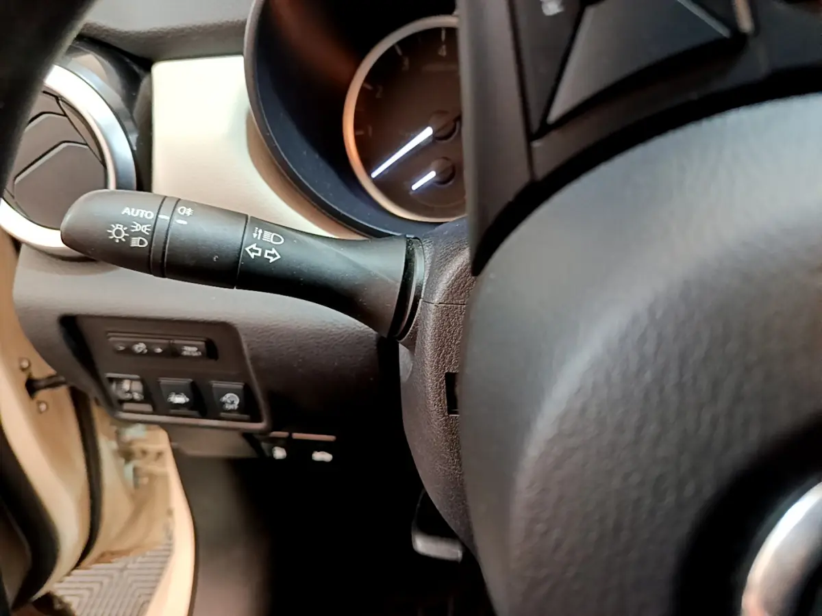 Gros plan sur le commodo gauche et le tableau de bord noir du Nissan Micra blanc, version IG-T 92 Acenta 2022.