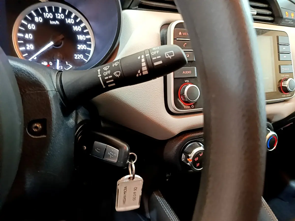 Vue rapprochée du tableau de bord et volant d'une Nissan Micra blanche 2022, avec clé insérée et commandes visibles.