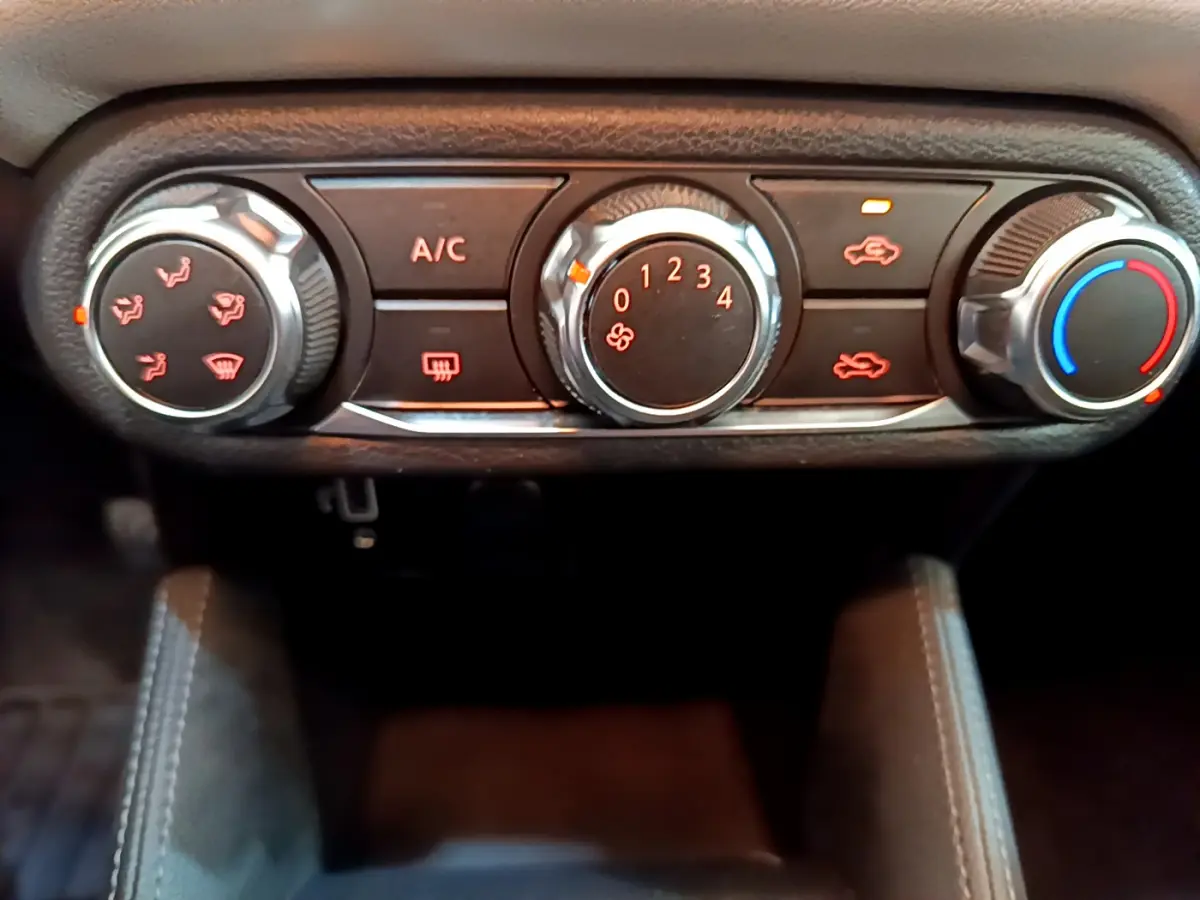 Gros plan sur les commandes de climatisation manuelle de la Nissan Micra IG-T 92 Acenta 2022, boutons noirs et chrome.