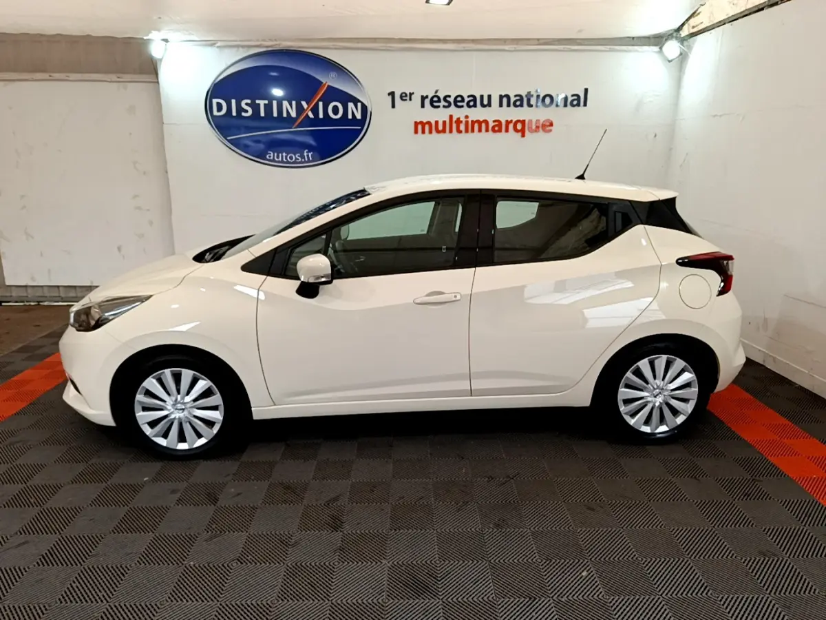Profil côté gauche d'une Nissan Micra blanche 2022 IG-T 92 Acenta dans un showroom avec sol noir et orange.