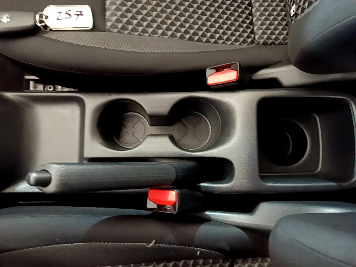 Vue plongeante sur la console centrale noire de la Nissan Micra Acenta 2022, avec frein à main et porte-gobelets.