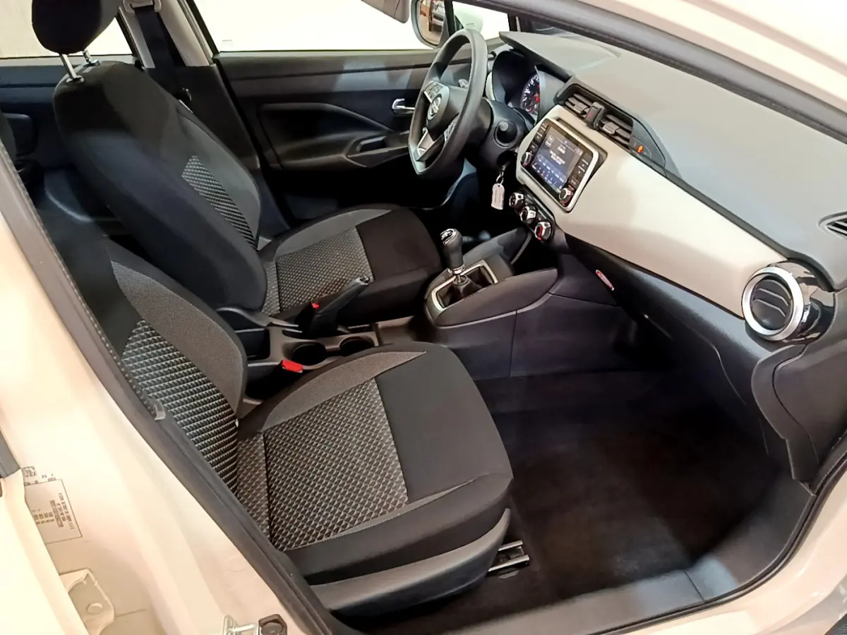 Vue intérieure côté conducteur de la Nissan Micra IG-T 92 Acenta 2022 avec sièges tissu noir et tableau de bord clair.