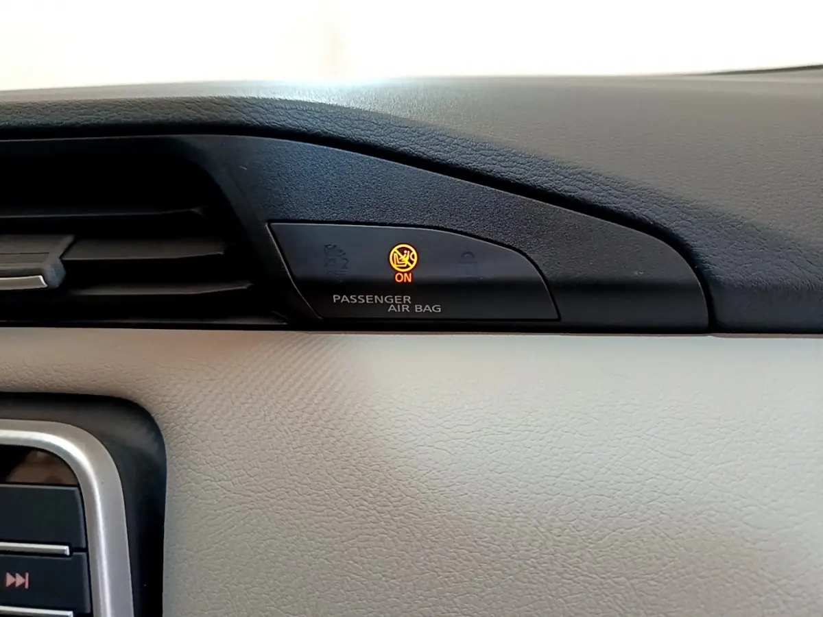 Gros plan sur le tableau de bord beige et noir du Nissan Micra blanc 2022, voyant airbag passager allumé en orange