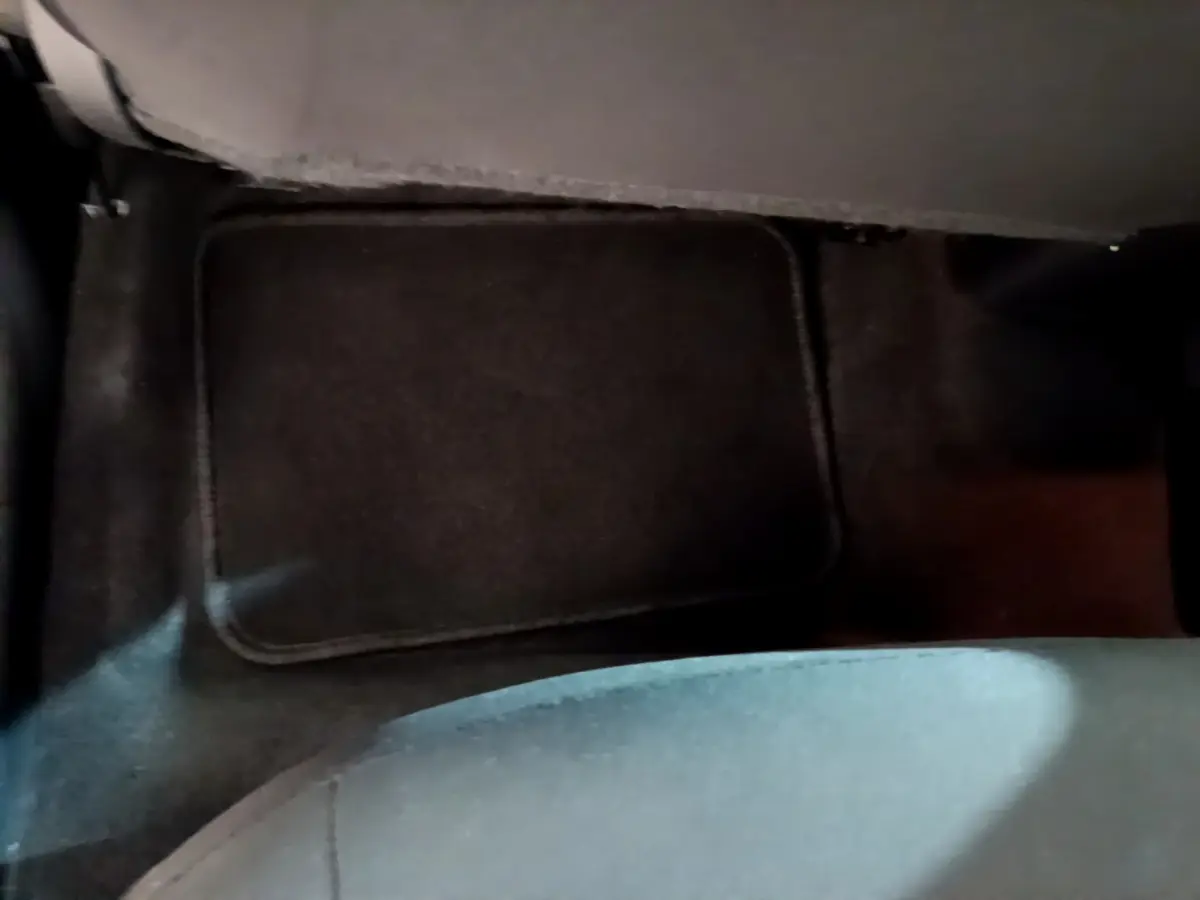 Vue rapprochée du tapis de sol noir au niveau du plancher arrière d'une Nissan Micra blanche 2022.