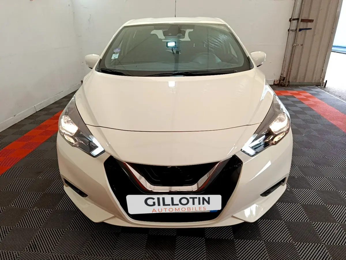 Vue frontale d'une Nissan Micra IG-T 92 Acenta blanche avec phares LED allumés dans un garage.