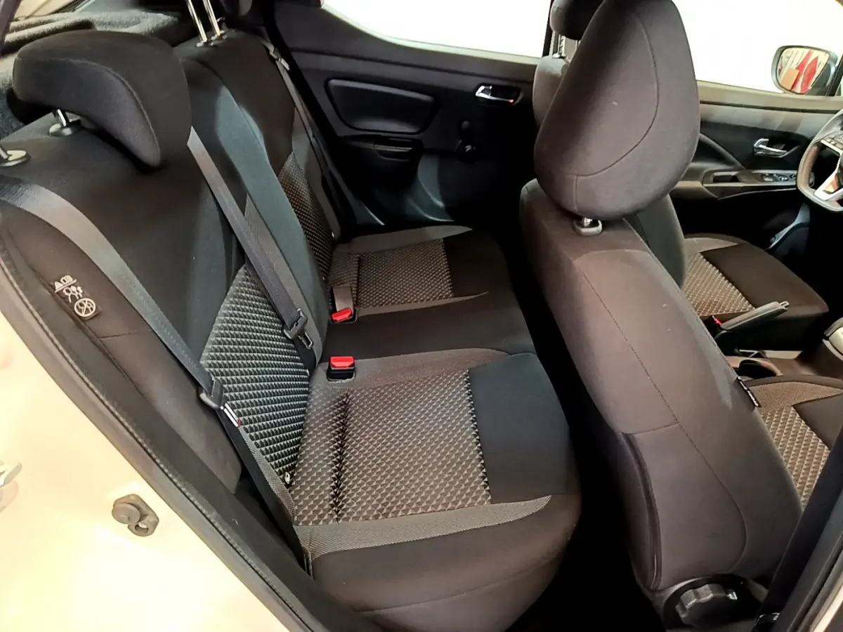 Vue intérieure côté gauche montrant les sièges arrière et avant noirs à motifs de la Nissan Micra blanche 2022.