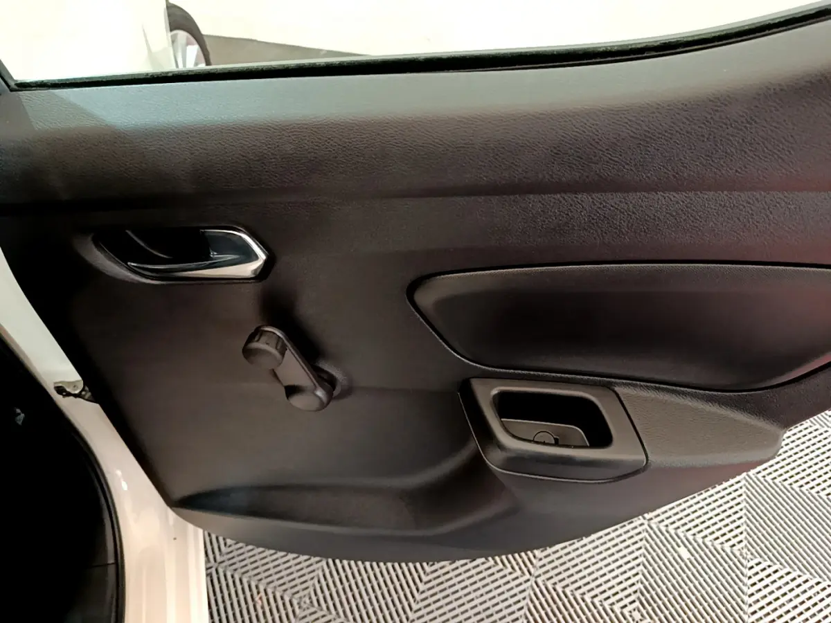 Vue rapprochée de la porte intérieure côté gauche d'une Nissan Micra blanche, avec manivelle de vitre manuelle.