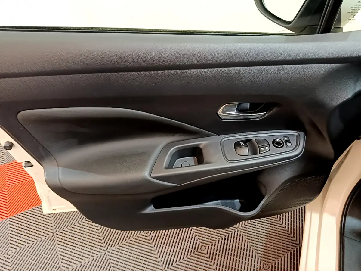 Vue rapprochée de la porte avant gauche blanche d'une Nissan Micra 2022 avec commandes électriques et poignée chromée.