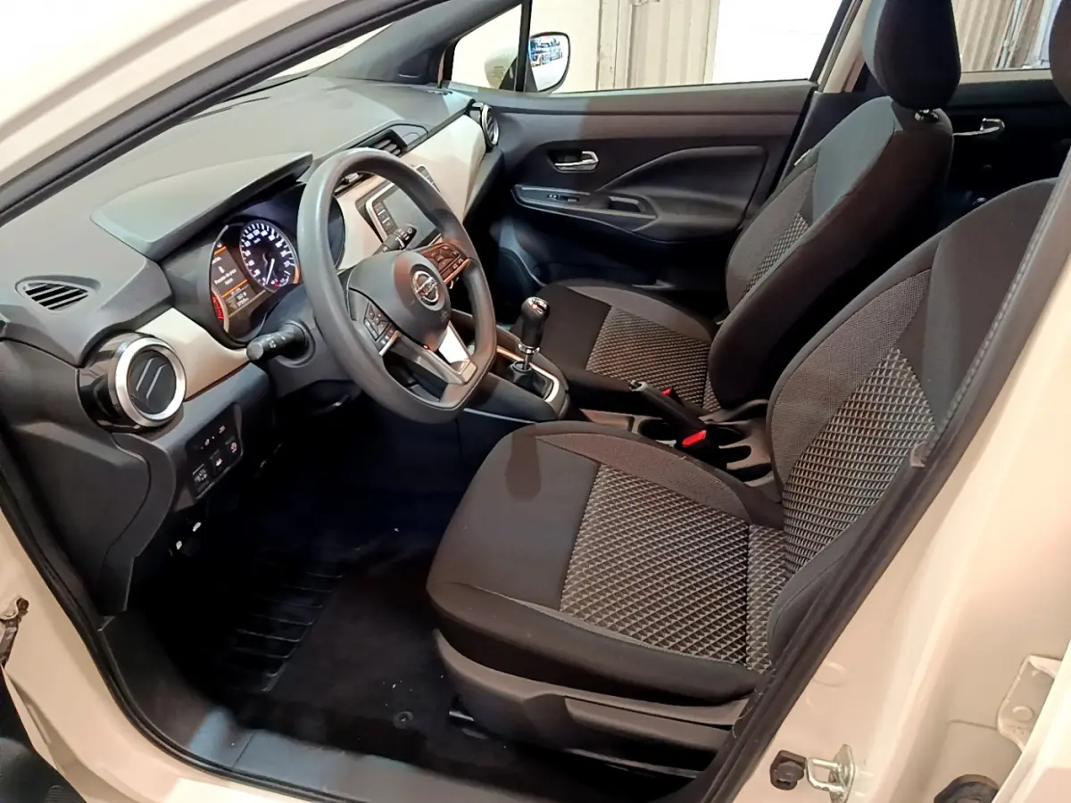 Intérieur avant de la Nissan Micra blanc 2022, vue côté conducteur montrant sièges noirs et tableau de bord moderne.