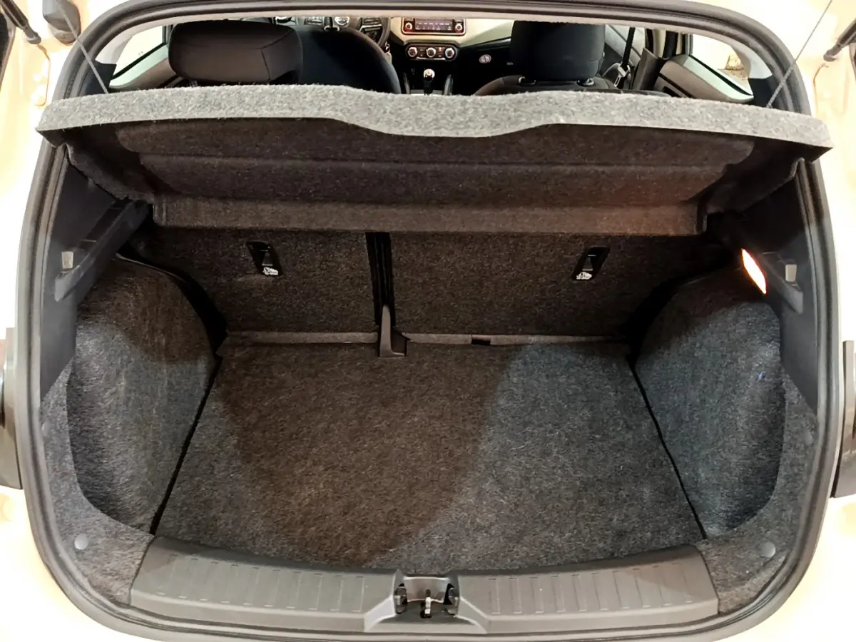 Coffre ouvert vu de l'arrière d'une Nissan Micra blanche 2022, intérieur gris avec tablette de séparation relevée.