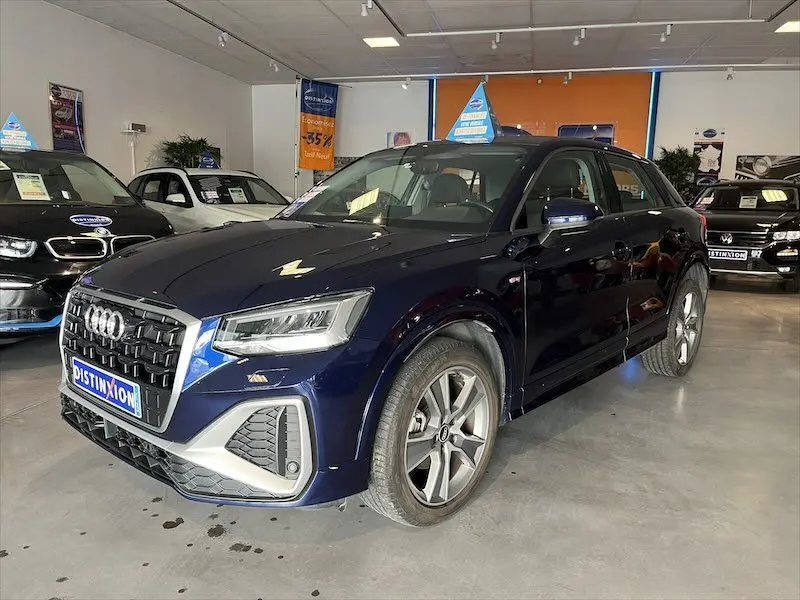 Audi Q2 30 TFSI S-Line bleu Navarre métal vue 3/4 avant droit en intérieur, calandre et jantes distinctives visibles