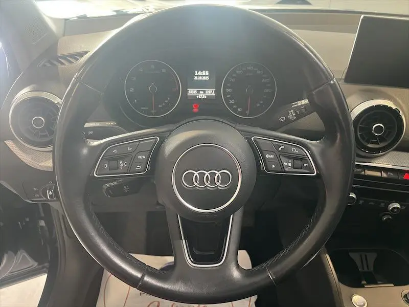 Vue intérieure centrée sur le volant cuir d'un Audi Q2 30 TFSI S-Line 2021 avec tableau de bord et écran multimédia.